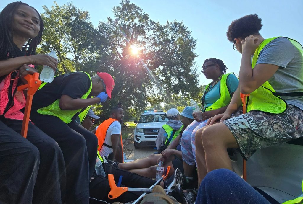 Volunteers in safety vests gather at sunrise before a neighborhood cleanup